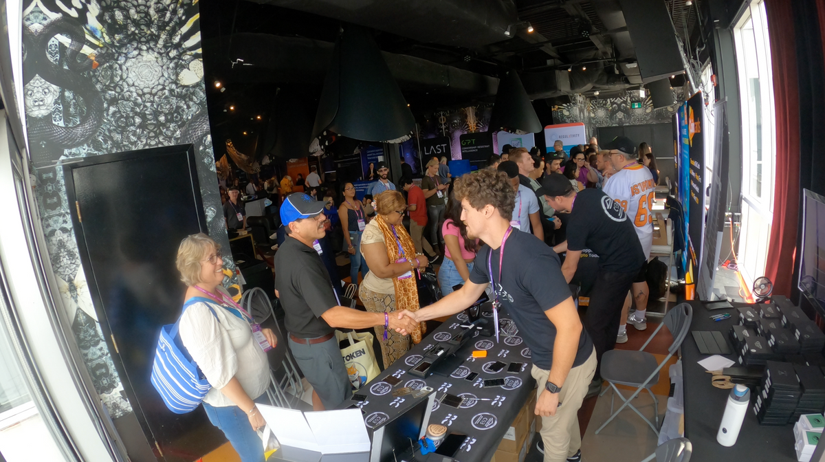 A Crypto Seed Bank™ team member shaking hands with a visitor at the Blockchain Futurist Conference booth.